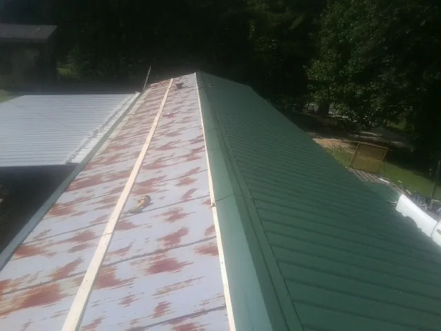 Old rusted panels beside newly installed green metal roofing — Wind Damage Roof Repair by Roofing Brothers in Roxbury Crossing