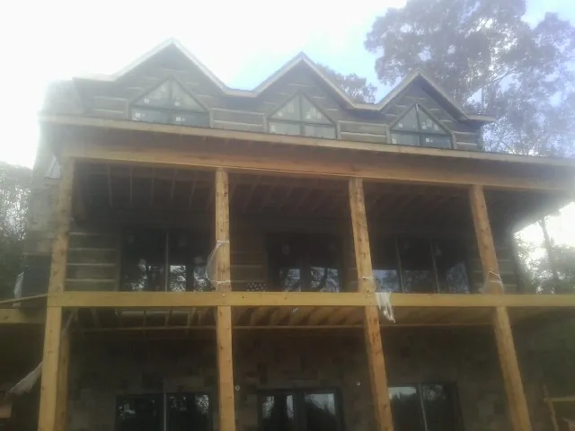 Dormers and porch framing on a large log home under construction — Roof Coating work by our crew in Roxbury Crossing