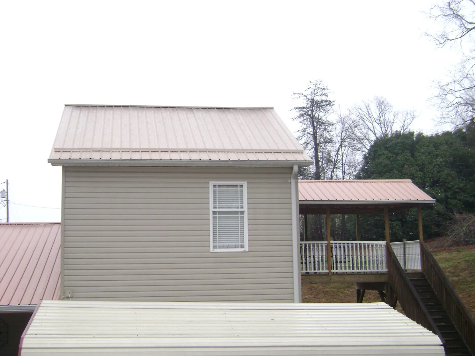 Tan metal roofs on a two story addition and attached porch, from a Roof Replacement job in Roxbury Crossing
